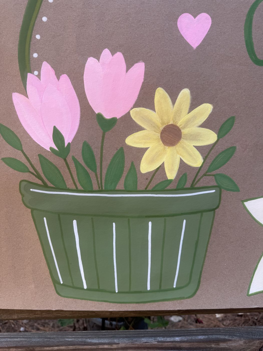 Close-up of a hand-painted green flower basket with pink tulips and a yellow daisy